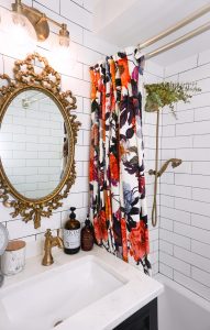 Vintage Gold Mirror in All White Subway Tile Bathroom | Floor to Ceiling White Subway Tile | Gold Bathroom Hardware | Anthropologie Floral Shower Curtain