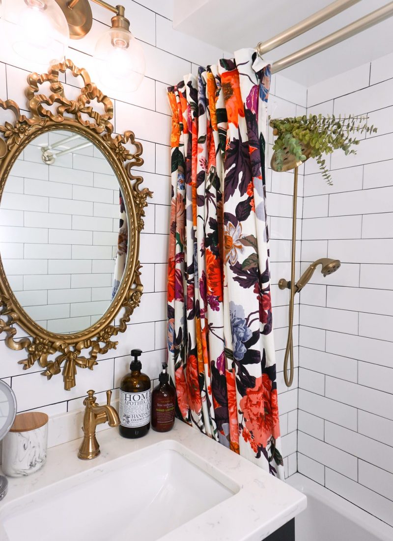 Vintage Gold Mirror in All White Subway Tile Bathroom | Floor to Ceiling White Subway Tile | Gold Bathroom Hardware | Anthropologie Floral Shower Curtain